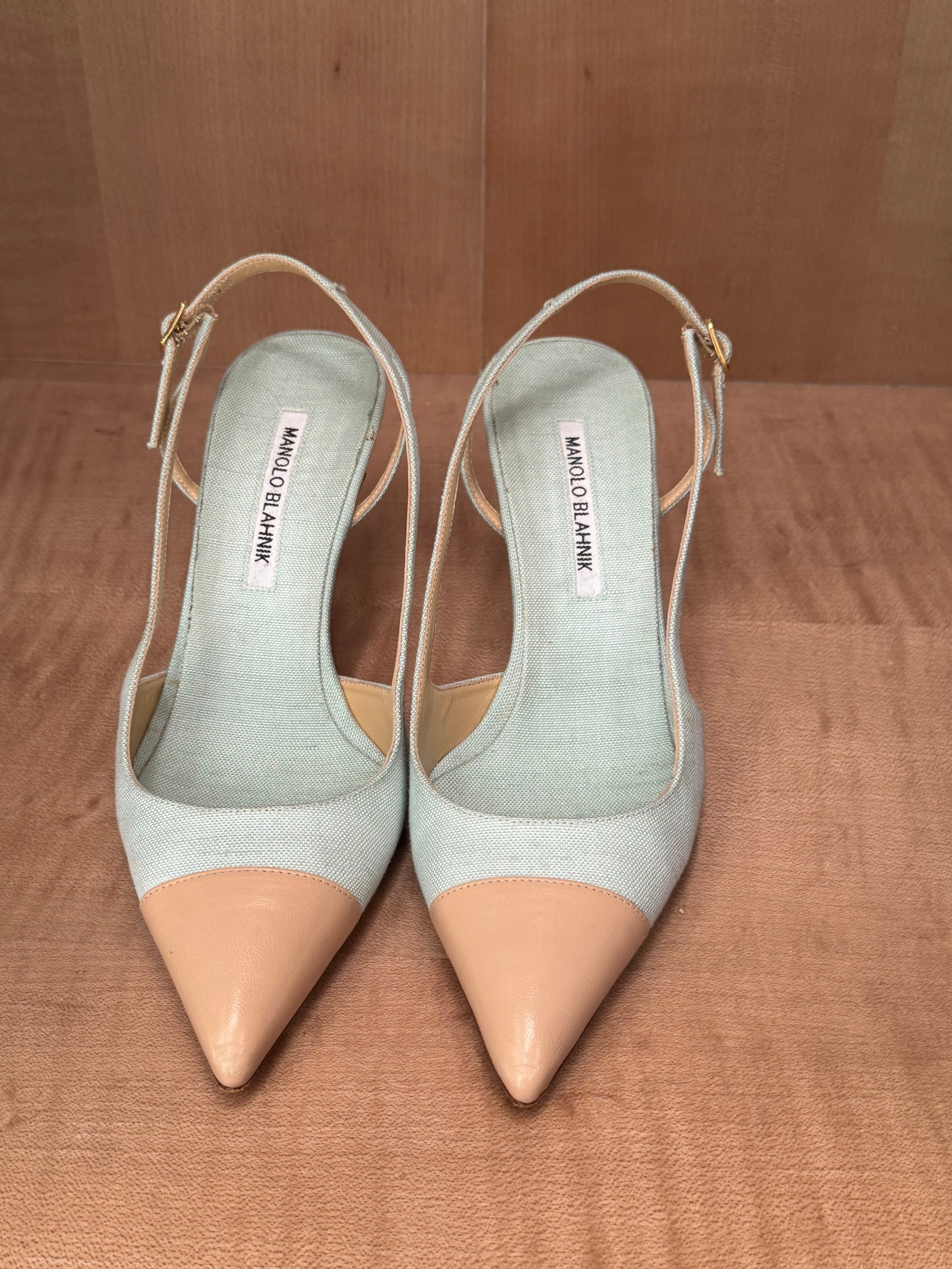 Pair of light blue Manolo Blahniks and beige pointed-toe shoes on a wooden surface
