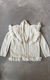 White knitted hoodie with tassels on a gray concrete surface